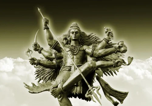 Multi-armed Kalabhairava statue holding a trident and sword against a cloudy sky for Hanuman Kalabhairava puja