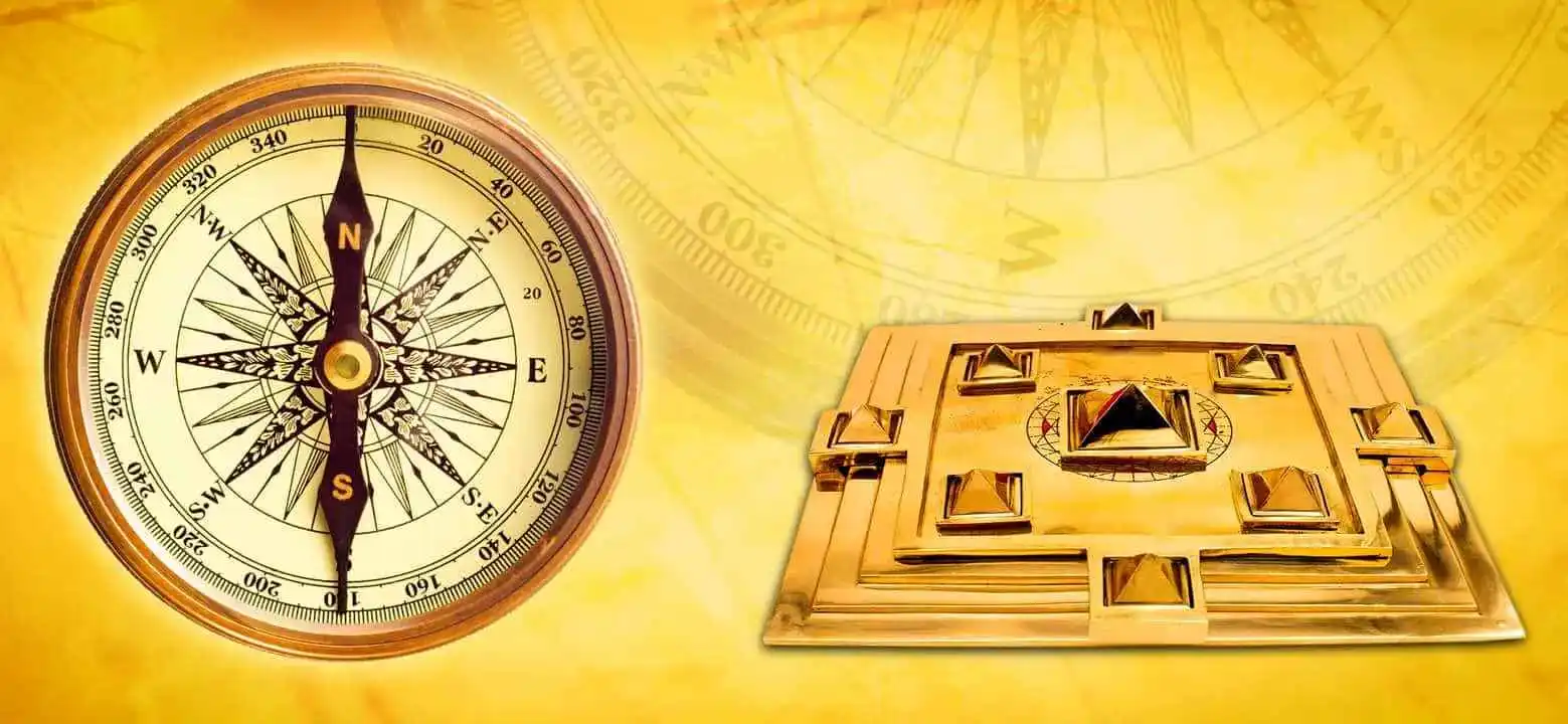 Brass directional compass beside a gold Vaastu pyramid yantra plate on a golden yellow background